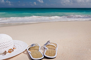 Sandals and sun hat on a sandy beach