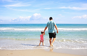 Father and daughter walking along a beach